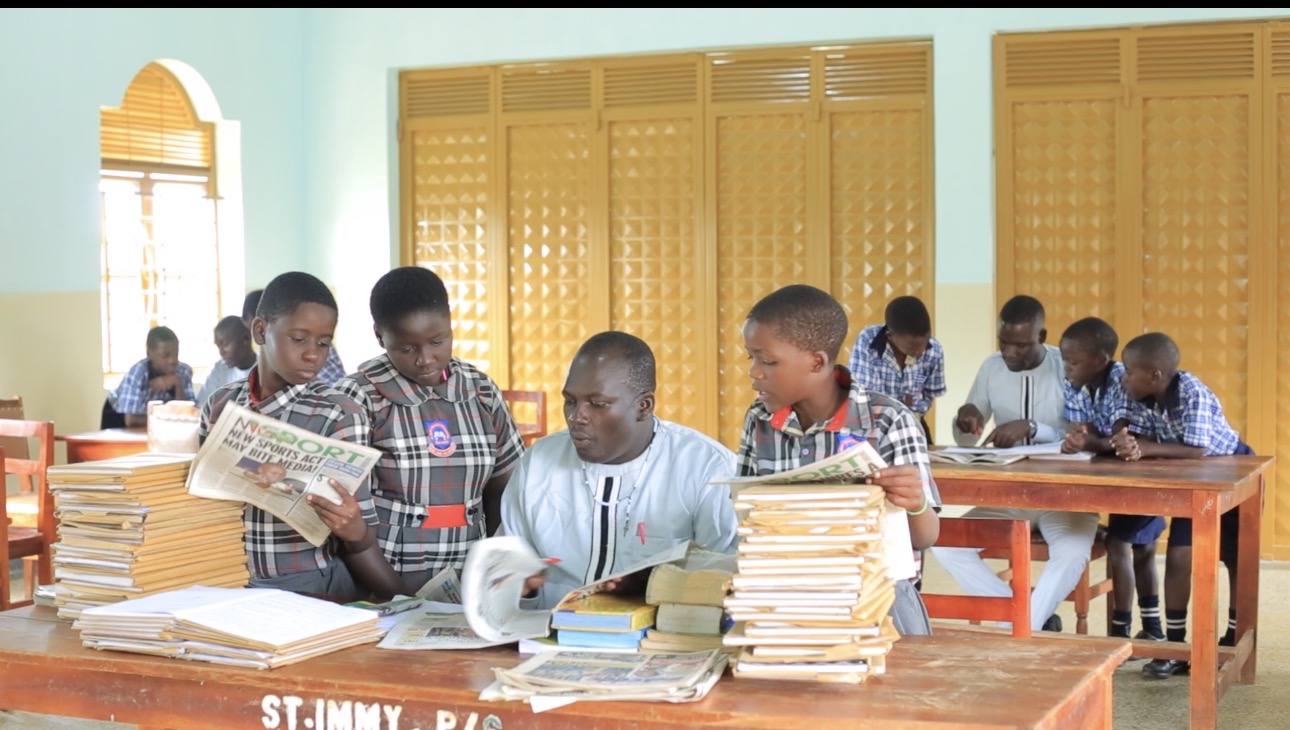 Head of English showing pupils the use of different materials in daily life and use of information such as reading News papers